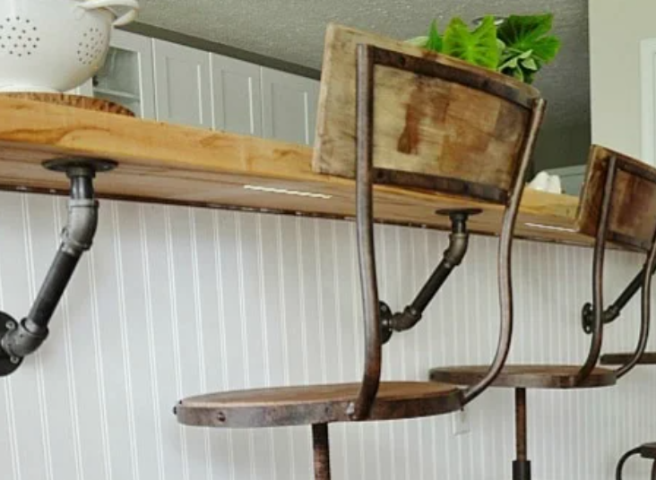 A thin white Strips Presence sensor fixed flat to the underside of a wooden counter edge, all but hidden from anyone sitting at the stools below it